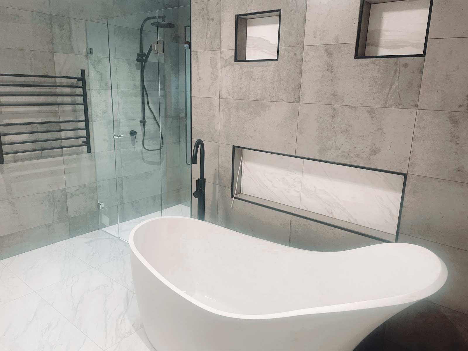 Finished bathroom with a freestanding bath, black tapware and a walk-in shower