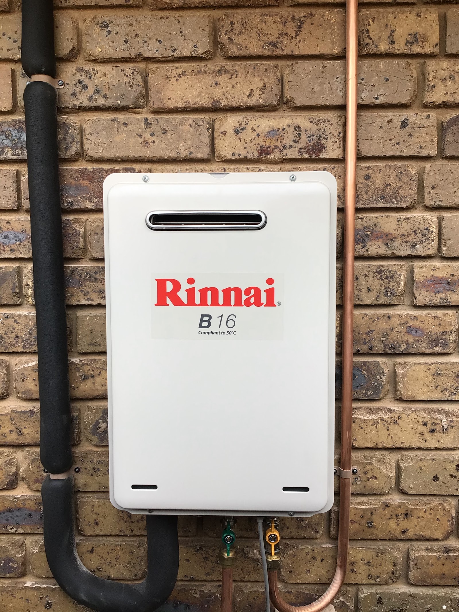 Continuous flow gas hot water unit installed on a brick wall with new copper pipework