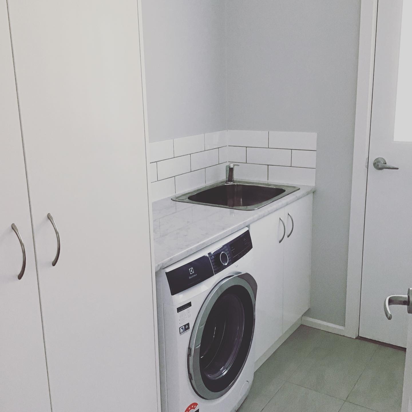 Laundry with a new sink, tapware and tiled splashback plumbed in